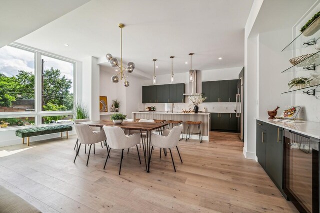 dining space with light wood-type flooring, beverage cooler, and sink