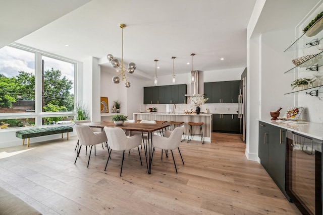 dining space featuring a chandelier, wine cooler, light wood-style flooring, and recessed lighting