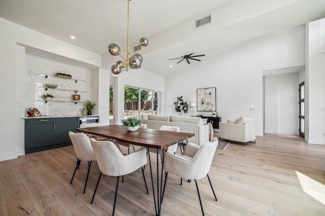 dining space with vaulted ceiling, ceiling fan with notable chandelier, and light wood-type flooring