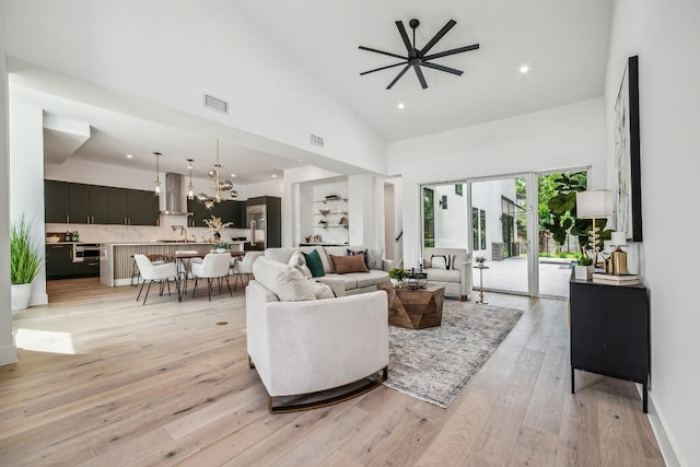 living room featuring light wood-type flooring, high vaulted ceiling, visible vents, and recessed lighting