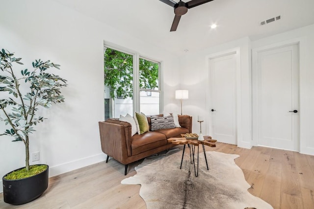 living area with a ceiling fan, visible vents, light wood-style flooring, and baseboards