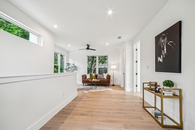 hall featuring baseboards, light wood-style flooring, and recessed lighting