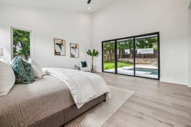 bedroom with access to exterior, a high ceiling, light hardwood / wood-style flooring, and ceiling fan