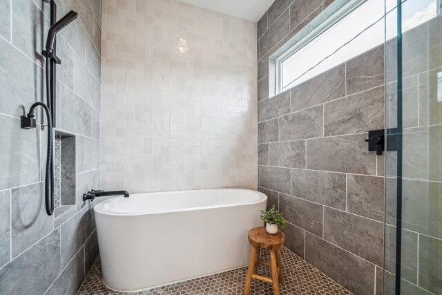 bathroom with tile patterned flooring, separate shower and tub, and tile walls