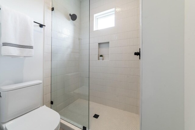 bathroom featuring a tile shower and toilet