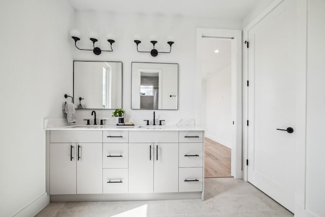 bathroom with double vanity, a sink, and baseboards