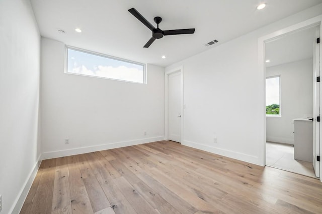 unfurnished bedroom featuring visible vents, multiple windows, and light wood-style flooring