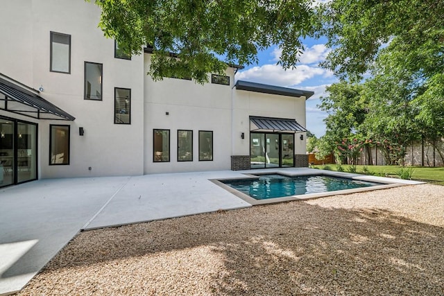 rear view of house with a fenced in pool, a standing seam roof, a patio, and stucco siding