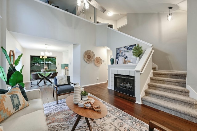 living area with stairs, hardwood / wood-style flooring, a fireplace, and baseboards