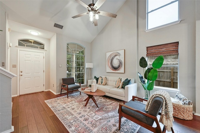 living area with visible vents, high vaulted ceiling, baseboards, and hardwood / wood-style floors