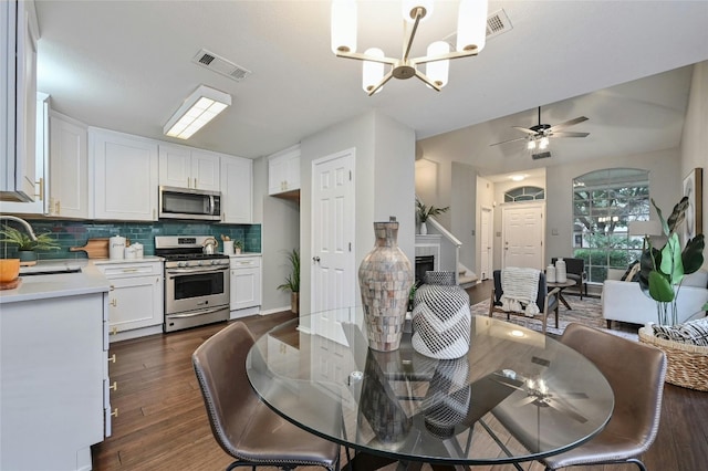 dining area with dark wood finished floors, visible vents, and ceiling fan with notable chandelier