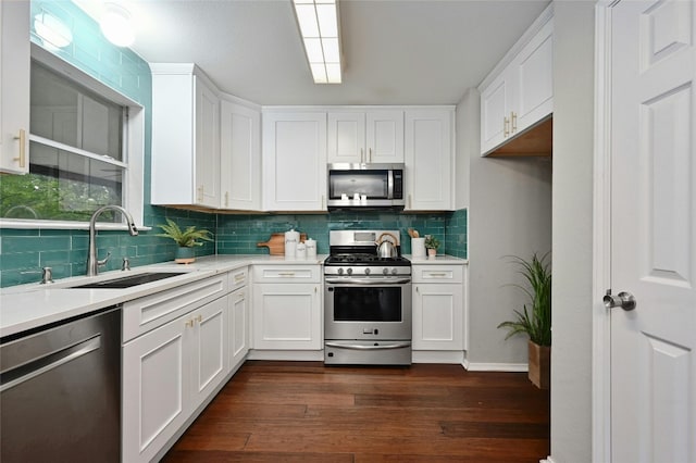 kitchen featuring dark wood-type flooring, a sink, white cabinetry, stainless steel appliances, and light countertops