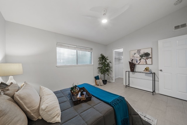 bedroom featuring a walk in closet, lofted ceiling, ceiling fan, and a closet