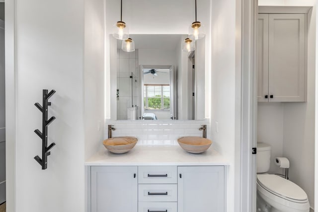 bathroom with vanity with extensive cabinet space, ceiling fan, toilet, and tasteful backsplash