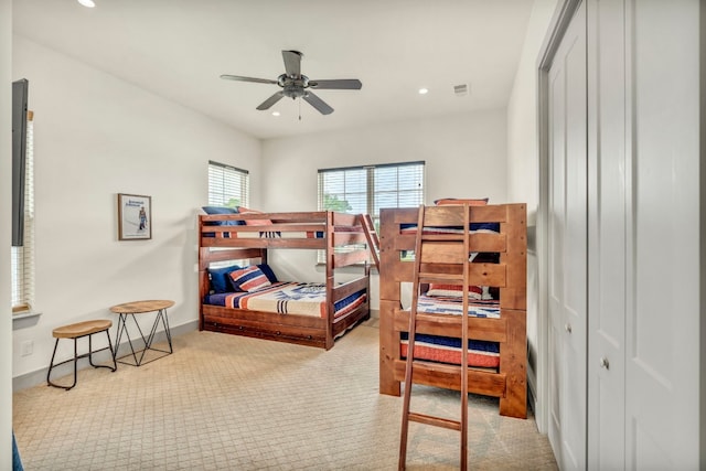 bedroom with a closet, ceiling fan, and light colored carpet