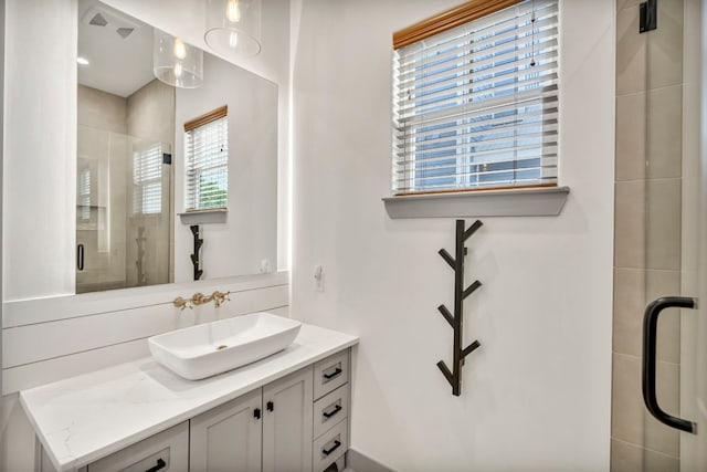 bathroom featuring a shower with door and vanity