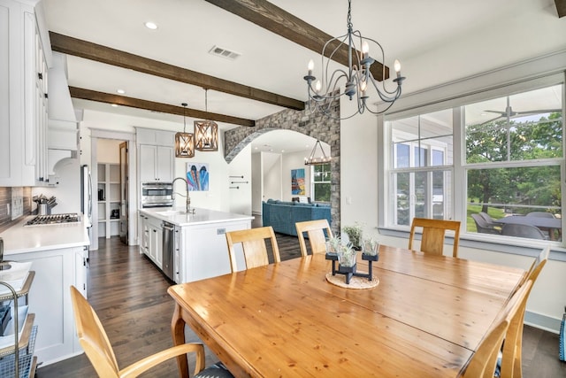 dining area with beamed ceiling, ceiling fan with notable chandelier, and dark wood-type flooring