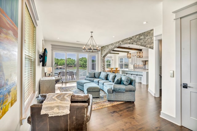 living room featuring sink, dark hardwood / wood-style flooring, and an inviting chandelier