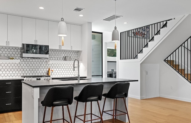 kitchen featuring decorative light fixtures, sink, tasteful backsplash, and light wood-type flooring