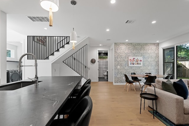 dining space featuring brick wall, sink, and light hardwood / wood-style floors