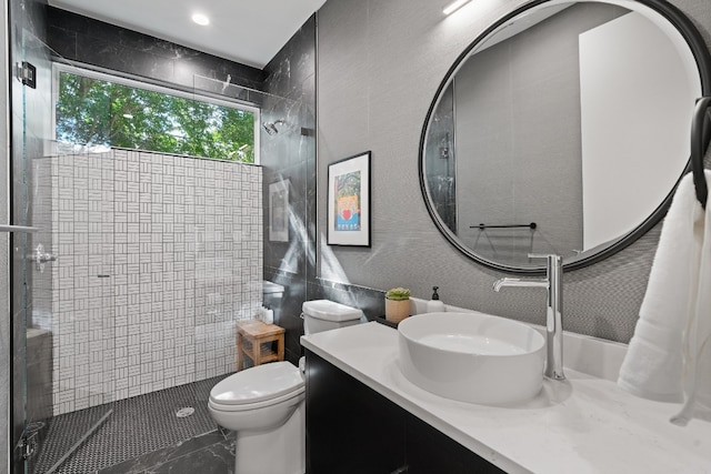 bathroom featuring tiled shower, toilet, and vanity