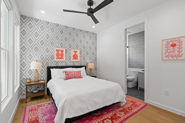 bedroom featuring ensuite bath, ceiling fan, and hardwood / wood-style flooring