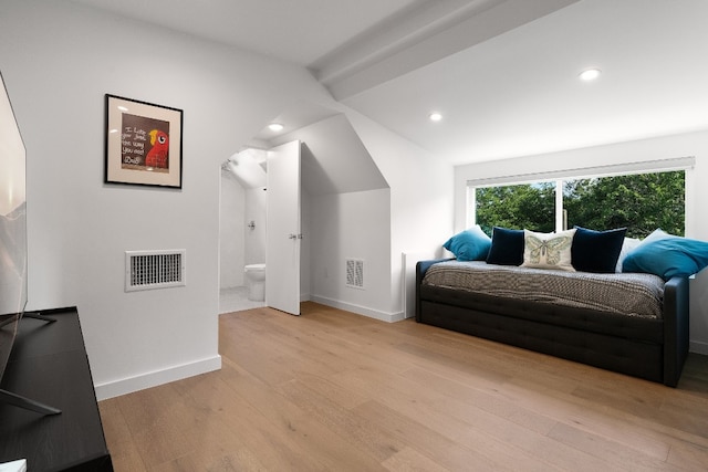 bedroom featuring vaulted ceiling with beams, connected bathroom, and light hardwood / wood-style floors