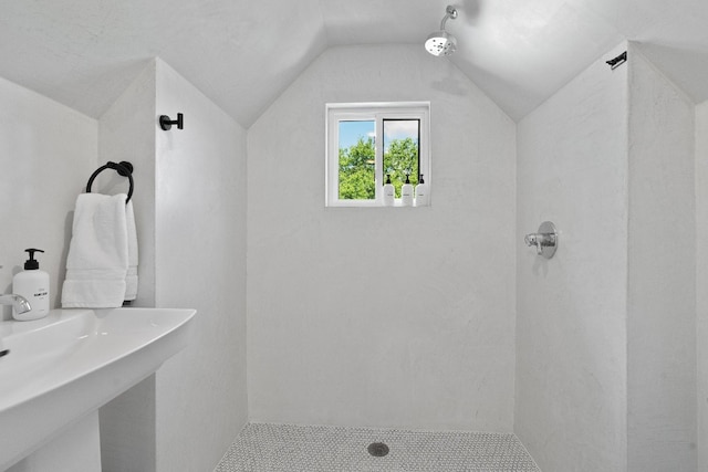 bathroom featuring tiled shower and lofted ceiling