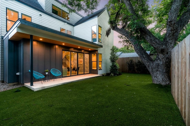 back house at dusk featuring a yard