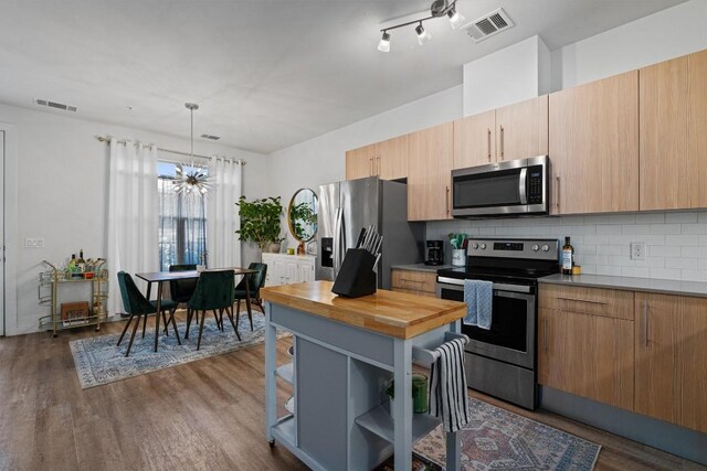 kitchen with appliances with stainless steel finishes, dark hardwood / wood-style floors, a chandelier, and tasteful backsplash