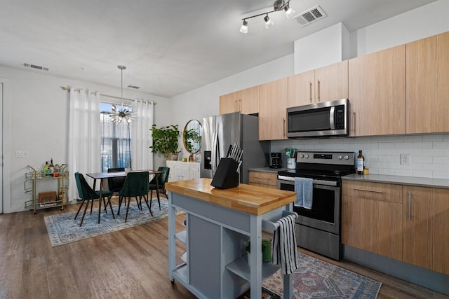 kitchen with appliances with stainless steel finishes, dark hardwood / wood-style flooring, decorative backsplash, decorative light fixtures, and a chandelier