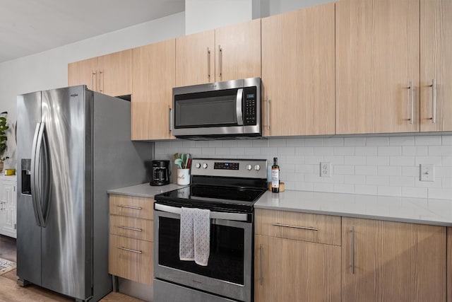 kitchen with light brown cabinets, appliances with stainless steel finishes, and tasteful backsplash