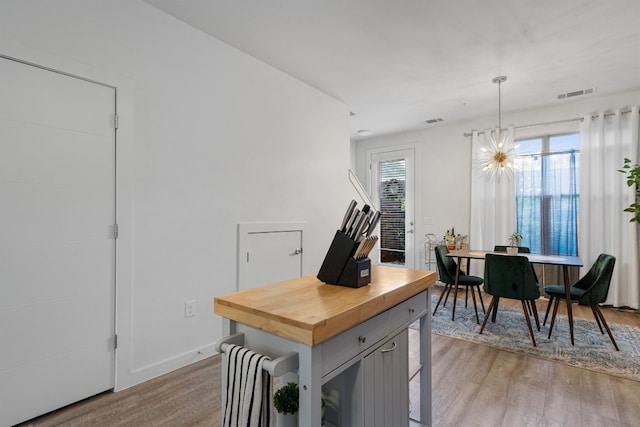 kitchen with hanging light fixtures, a healthy amount of sunlight, and light hardwood / wood-style floors