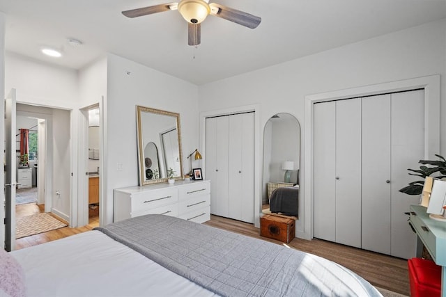 bedroom with light hardwood / wood-style floors, ceiling fan, and multiple closets