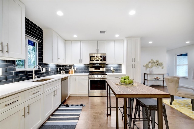 kitchen with white cabinets, stainless steel appliances, decorative backsplash, and sink