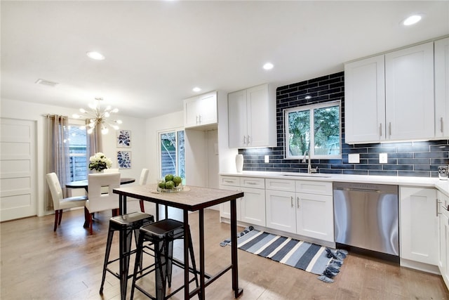 kitchen featuring light hardwood / wood-style floors, sink, white cabinetry, stainless steel dishwasher, and backsplash