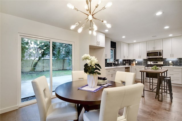 dining space with light wood-type flooring and a notable chandelier