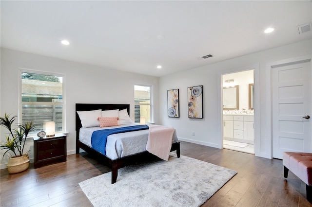 bedroom with ensuite bathroom and dark wood-type flooring