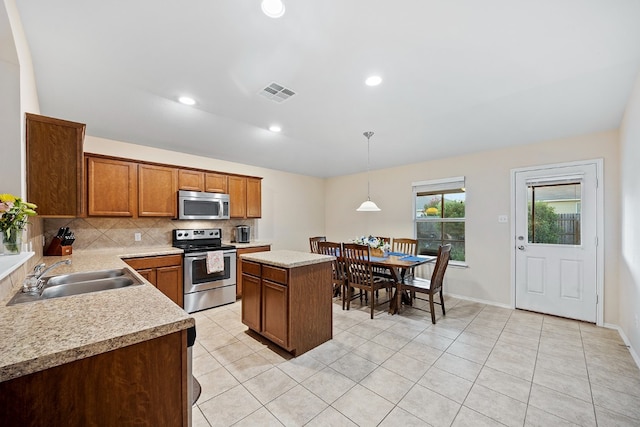 kitchen featuring sink, a center island, stainless steel appliances, pendant lighting, and light tile patterned flooring