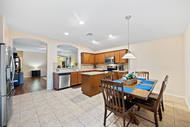 kitchen featuring appliances with stainless steel finishes, a center island, pendant lighting, and light tile patterned flooring