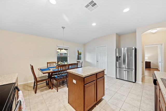 kitchen featuring stainless steel fridge, stove, lofted ceiling, decorative light fixtures, and a kitchen island