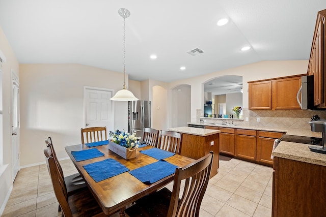 dining room with ceiling fan, light tile patterned floors, sink, and vaulted ceiling