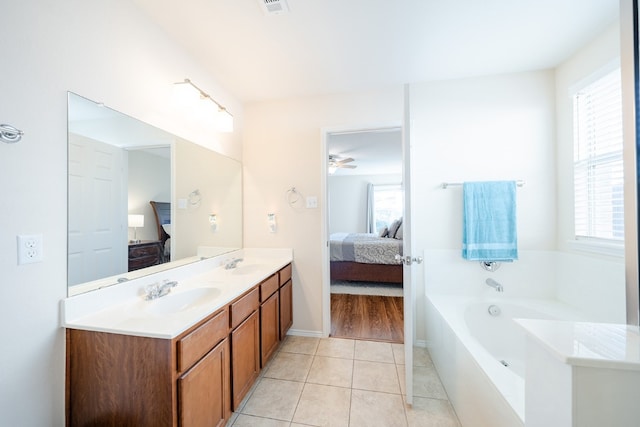 bathroom featuring tile patterned flooring, vanity, a wealth of natural light, and a tub