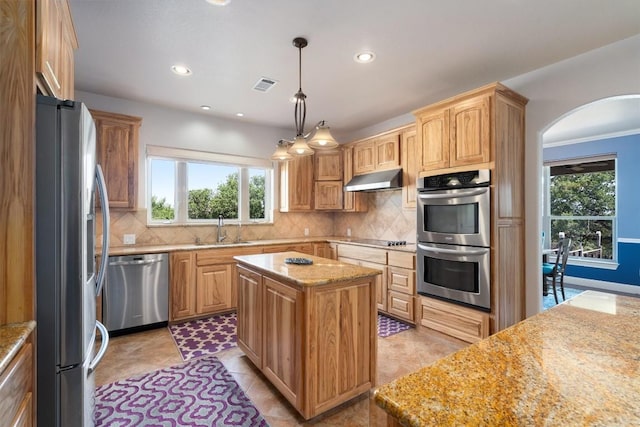 kitchen featuring light stone counters, stainless steel appliances, a center island, and sink