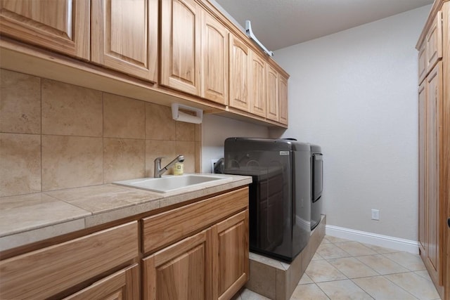 laundry room with light tile patterned flooring, cabinets, sink, and washing machine and clothes dryer