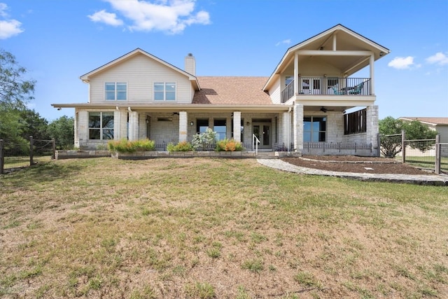 view of front of house with a balcony, ceiling fan, and a front lawn