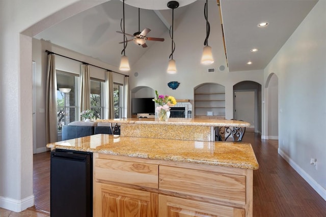 kitchen featuring light stone countertops, a center island, light brown cabinets, and ceiling fan