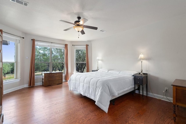 bedroom featuring ceiling fan, dark hardwood / wood-style floors, and multiple windows