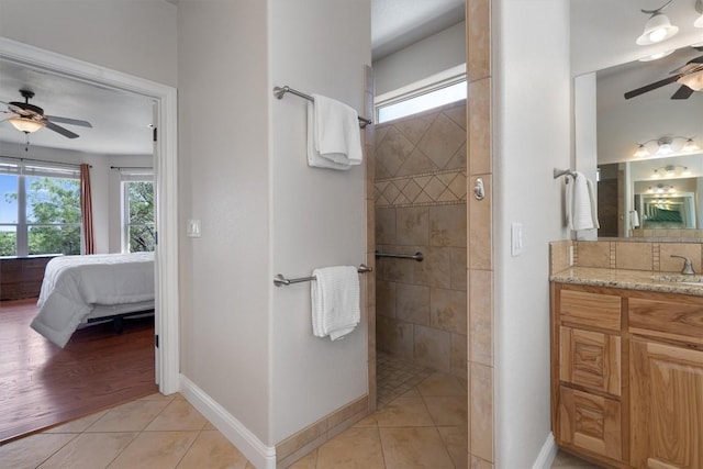 bathroom with ceiling fan, tiled shower, vanity, and tile patterned flooring