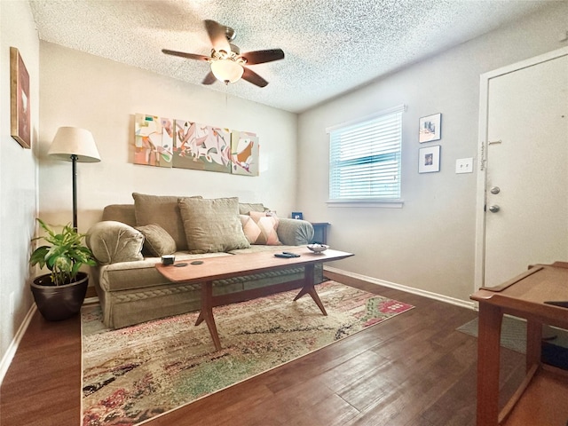 living room featuring a textured ceiling, dark wood-type flooring, and ceiling fan